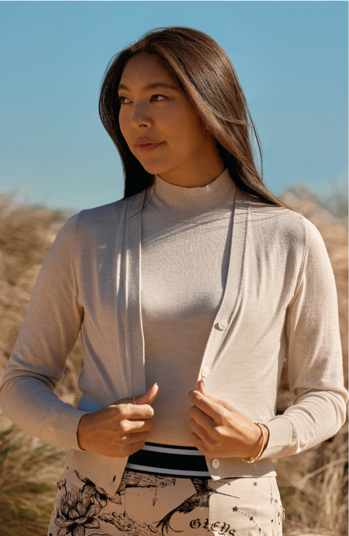 woman in a beige cardigan in a desert landscape